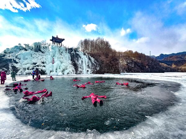 سياح يرتدون معدات واقية، أو ما يعرف ببدلات صيد الكركند، يستمتعون بمشاهدة الجليد العائم في جبل "يودو" خلال فصل الشتاء، في بكين، الصين. - سبوتنيك عربي
