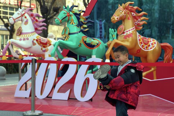 طفل يقف لالتقاط الصور بالقرب من الزينة التي تم وضعها استعداداً لرأس السنة القمرية الصينية لعام الحصان في بكين، الأربعاء 4 فبراير 2026. - سبوتنيك عربي