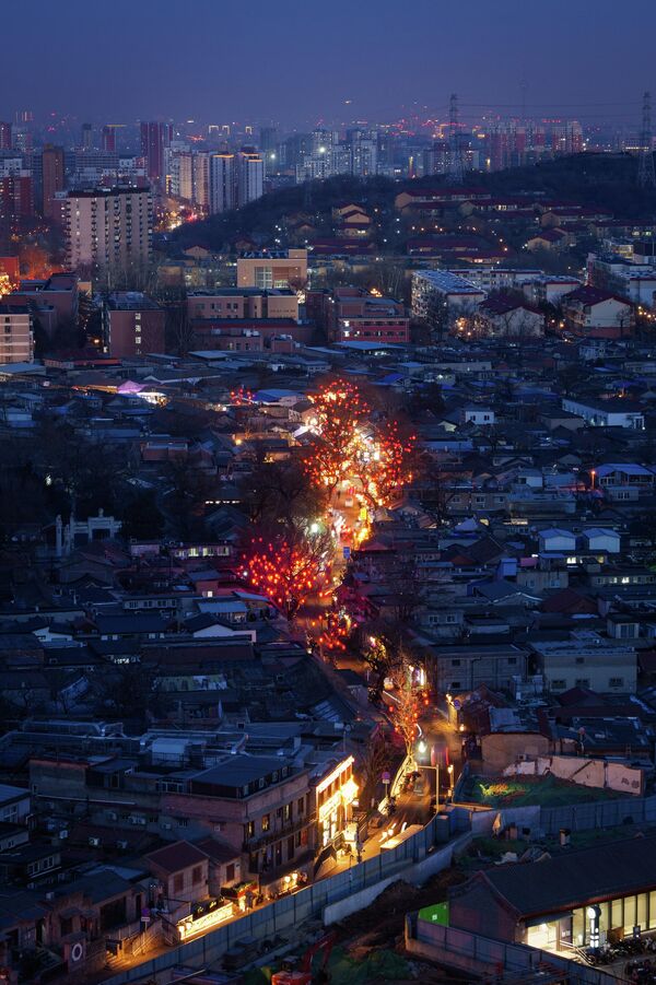 أضواء المدينة تضيء شارعاً تصطف على جانبيه الفوانيس الحمراء احتفالاً برأس السنة القمرية الجديدة في منطقة موديكو، ضواحي بكين، الصين، يوم الاثنين 2 فبراير 2026. - سبوتنيك عربي