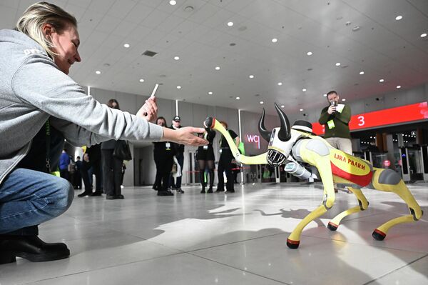صورة لكلب آلي، في معرض "كازان أغرو"، وهو يقوم بمد طرف من أطرافه لمصافحة إحدى الفتيات. - سبوتنيك عربي