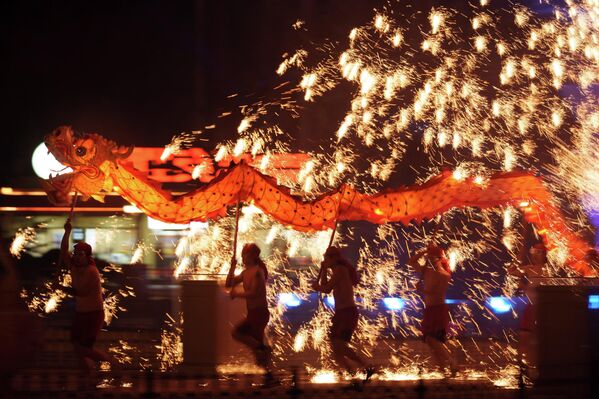 يحمل فنانو الألعاب النارية تنينًا خلال عرض للألعاب النارية المصنوعة من الحديد المنصهر والمعروف باسم أزهار التنين الناري الفولاذية قبل احتفالات رأس السنة القمرية في مدينة ملاهي على مشارف بكين، الصين. - سبوتنيك عربي