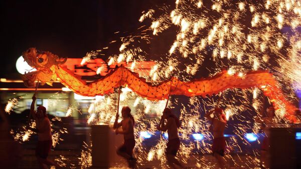 يحمل فنانو الألعاب النارية تنينًا خلال عرض للألعاب النارية المصنوعة من الحديد المنصهر والمعروف باسم أزهار التنين الناري الفولاذية قبل احتفالات رأس السنة القمرية في مدينة ملاهي على مشارف بكين، الصين. - سبوتنيك عربي