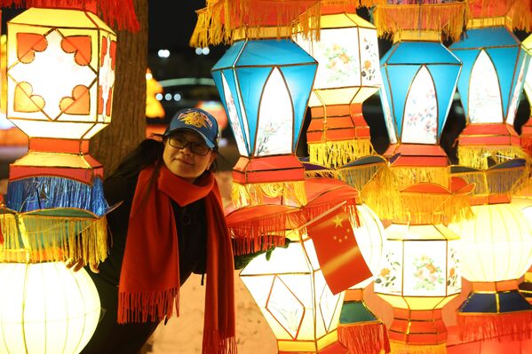 امرأة صينية تظهر بين مجموعة فوانيس ملوّنة بألوان زاهية مضائة في سان بطرسبورغ خلال احتفالات رأس السنة الصينية الجديد. - سبوتنيك عربي