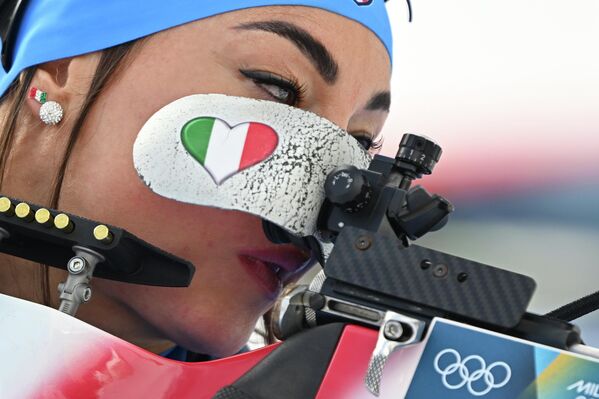 متسابقة من إيطاليا تقف في ميدان الرماية، تصوّب نحوالهدف، وترسم على وجهها علم بلادها - سبوتنيك عربي