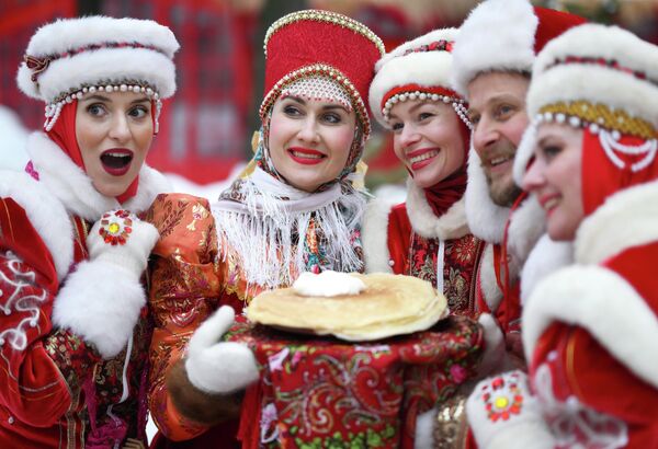 مشاركون في عيد "ماسلينيتسا" يلبسون زيًا شتويًا تقليديًا بالأحمر والأبيض ويحملون أطباقا تقليدية للاحتفال بالعيد، في شارع "تفيرسكايا" في موسكو، روسيا - سبوتنيك عربي