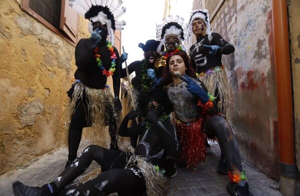 مشاركون في الكرنفال يرتدون ملابس تنكرية بزي الإنسان القديم ويضعون على رؤوسهم ريشا باللونين الأبيض والأسود. - سبوتنيك عربي