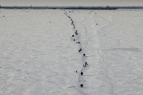 أشخاص يسيرون وسط خليج فنلندا المتجمد في سان بطرسبورغ.  - سبوتنيك عربي