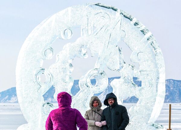 مشاركون في مهرجان فنون الجليد الشتوي الـ12، مباشرة على بحيرة "بايكال"، عند منحوتة "الساعة الذهبية"، في قرية ليستفيانكا، روسيا، 2026 - سبوتنيك عربي