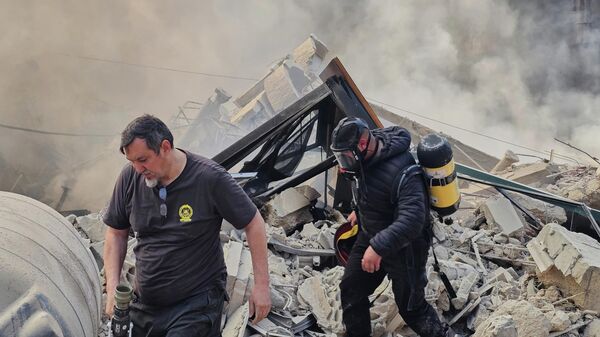 Пожарные осматривают обломки, из-под которых поднимается дым после израильского авиаудара в Дахие, южном пригороде Бейрута, Ливан - سبوتنيك عربي