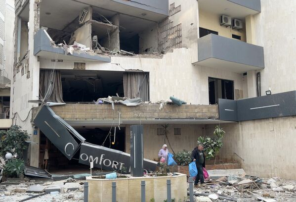 نزلاء الفندق يحملون أمتعتهم أثناء مغادرتهم فندقا متضررا تعرض لغارة جوية إسرائيلية في الحازمية، شرقي بيروت. - سبوتنيك عربي