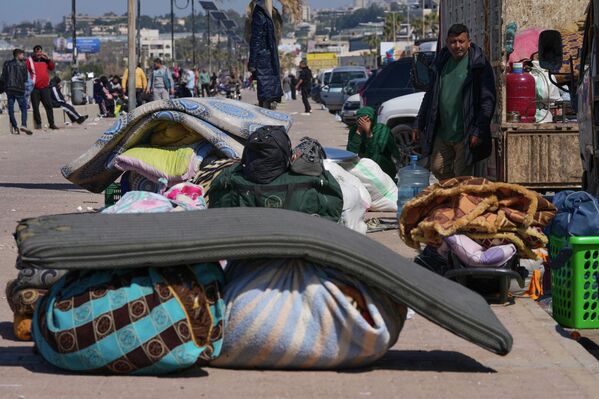 مدنيون نازحون فارون من الغارات الجوية الإسرائيلية في جنوب لبنان، يجلسون بجوار أمتعتهم على رصيف كورنيش في مدينة صيدا. - سبوتنيك عربي