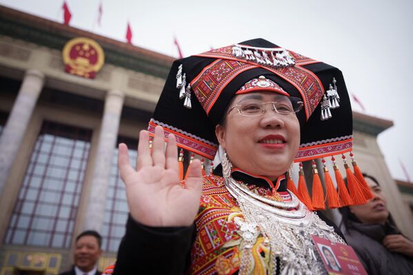 إحدى المندوبات تلوح بيدها أثناء مغادرتها الجلسة الافتتاحية للمؤتمر الاستشاري السياسي للشعب الصيني. - سبوتنيك عربي