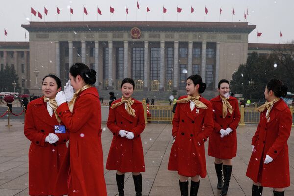 يقف الحضور وسط تساقط الثلوج في ميدان تيانانمن، قبل الجلسات الافتتاحية للمؤتمر الاستشاري السياسي للشعب الصيني والمجلس الوطني لنواب الشعب في بكين في الصين. - سبوتنيك عربي