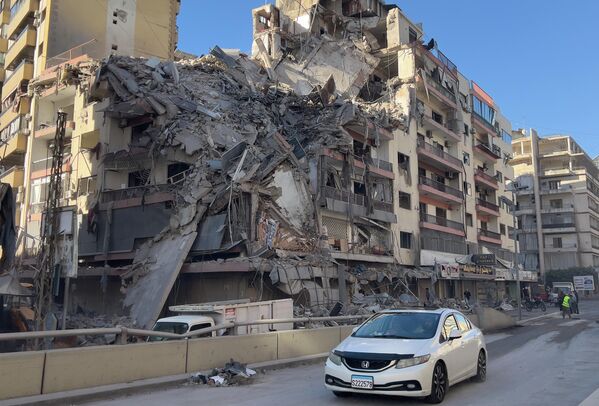سيارة تمر أمام مبنى مدمر تعرض لغارة جوية إسرائيلية في الضاحية الجنوبية لبيروت. - سبوتنيك عربي