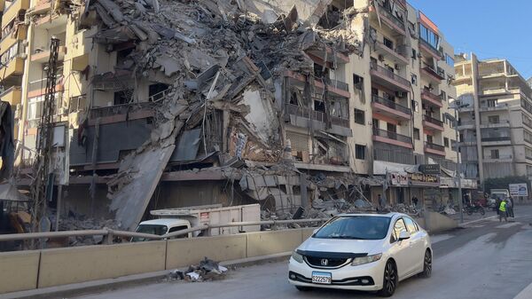 سيارة تمر أمام مبنى مدمر تعرض لغارة جوية إسرائيلية في الضاحية الجنوبية لبيروت. - سبوتنيك عربي