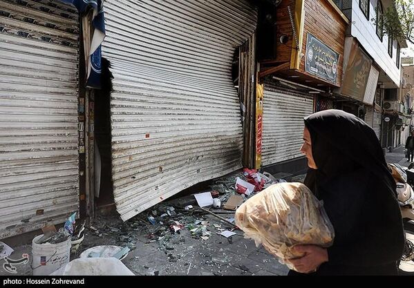 امرأة في أحد شوارع طهران تنظر إلى الأضرار، التي لحقت بالمحال التجارية، نتيجة الغارات الأمريكية - الإسرائيلية على المباني السكنية - سبوتنيك عربي