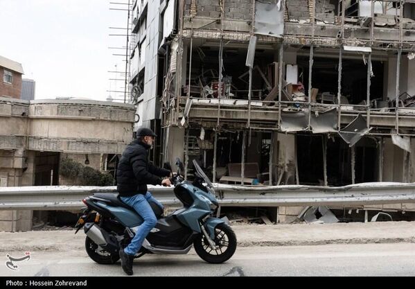صورة تظهر شابًا يستقل دراجة نارية أمام  مستشفى "غاندي" في طهران، الذي تضرر بشكل كبير نتيجة الضربات الأمريكية - سبوتنيك عربي