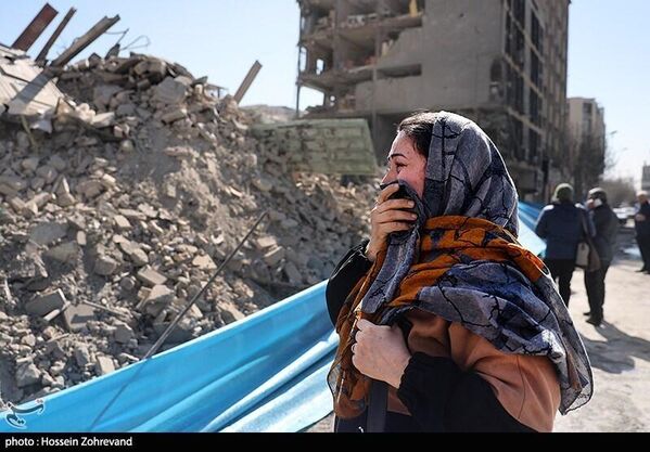 امرأة تبكي بحسرة وهي تشاهد حجم الدمار الذي لحق بالمباني السكنية في العاصمة طهران - سبوتنيك عربي