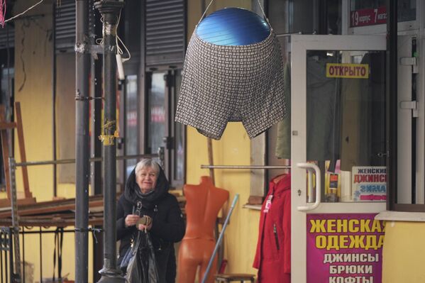 سيدة تنظر إلى ملابس داخلية معلقة على كرة لجذب الزبائن أمام متجر لبيع الملابس الداخلية في سوق للملابس في سان بطرسبورغ. - سبوتنيك عربي