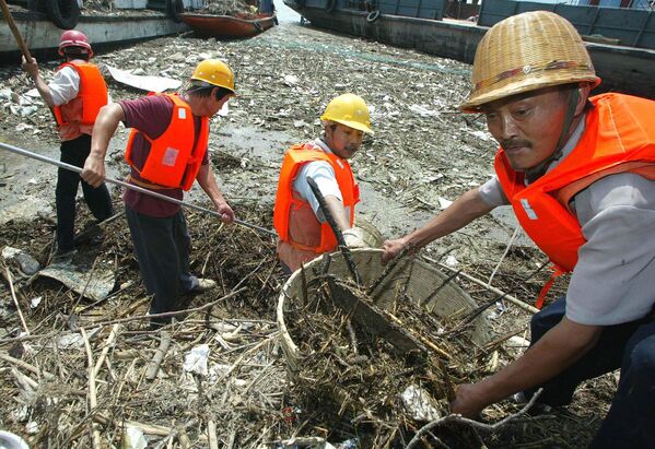 تُظهر هذه الصورة الأرشيفية، من عام 2003، عمالًا يُزيلون المخلفات العائمة  على نهر اليانغتسي في مدينة ييتشانغ بمقاطعة هوبي الصينية. - سبوتنيك عربي
