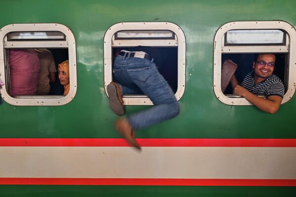 مسافرون عائدون إلى ديارهم، يتنافسون للصعود إلى القطار في محطة كمالابور للسكك الحديدية،  في بنغلاديش. - سبوتنيك عربي