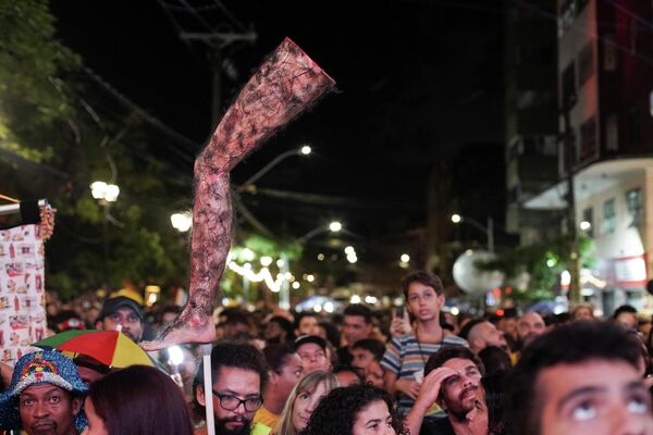  رجل يحمل ساقًا مشعرة بشكل مصطنع، في إشارة إلى فيلم "العميل السري"، بينما يتجمع الناس لمشاهدة البث المباشر لحفل توزيع جوائز الأوسكار في سينما "ساو لويز" في البرازيل. - سبوتنيك عربي