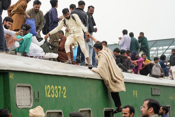 أشخاص يستقلون قطار ركاب مزدحم للوصول إلى منازلهم عشية عطلة عيد الفطر في محطة للسكك الحديدية في لاهور، باكستان - سبوتنيك عربي