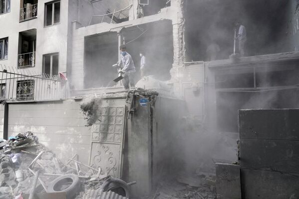 متطوعون يقومون بإزالة الأنقاض من مبنى سكني تضرر بعد استهداف مركز شرطة قريب، وذلك جراء الهجوم الأمريكي الإسرائيلي على العاصمة الإيرانية طهران. - سبوتنيك عربي