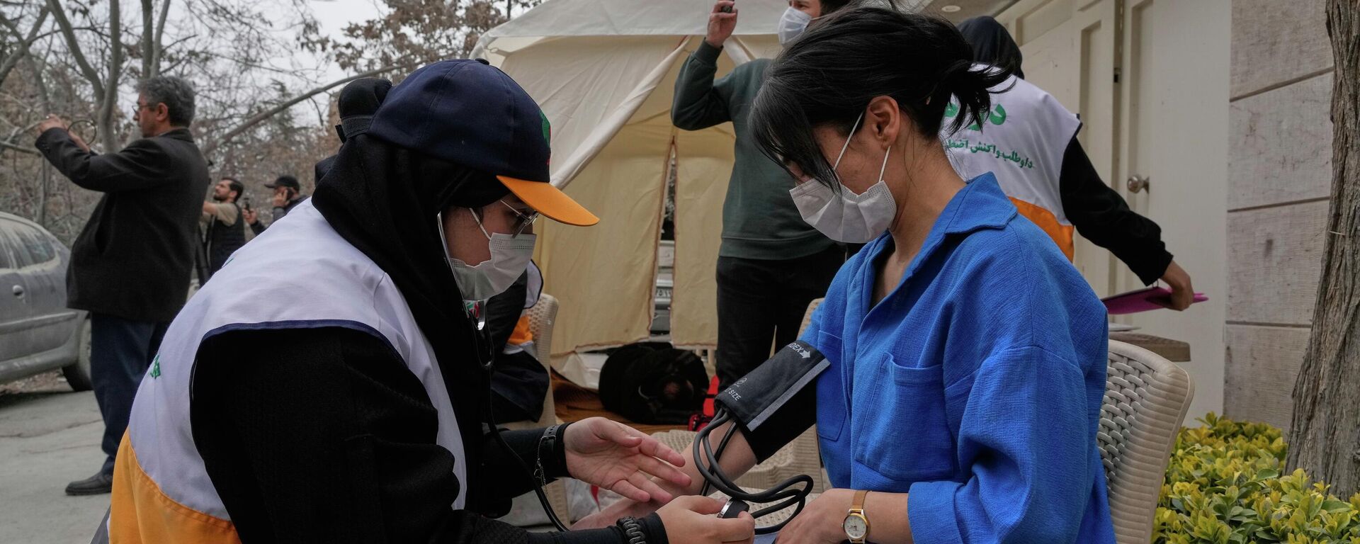 يقوم أحد المسعفين بقياس ضغط دم امرأة في أحد المواقع التي تعرضت للقصف الأمريكي الإسرائيلي في العاصمة طهران. - سبوتنيك عربي, 1920, 12.04.2026