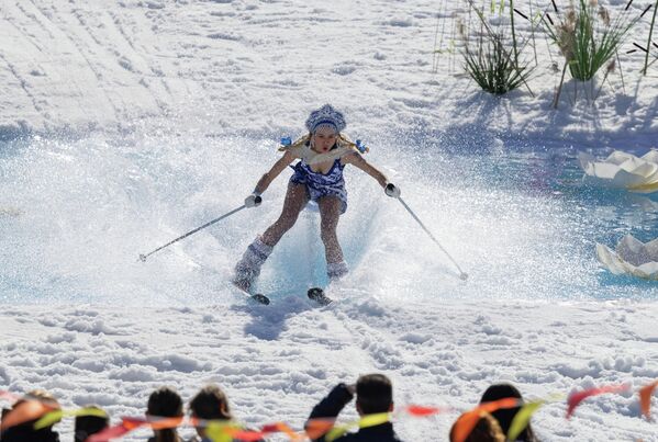 صورة لمتزلج يرتدي زيًا احتفاليًا يحاول عبور بركة مياه عند سفح منحدر خلال مشاركته في فعالية تُختتم بها فعاليات موسم التزلج في منتجع فوروبيوفي غوري في موسكو، روسيا. - سبوتنيك عربي