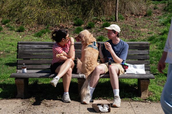 صورة تظهر شخصان ومعهم كلبهم في الوسط، جالسون في حديقة ميريديان هيل، واشنطن. - سبوتنيك عربي