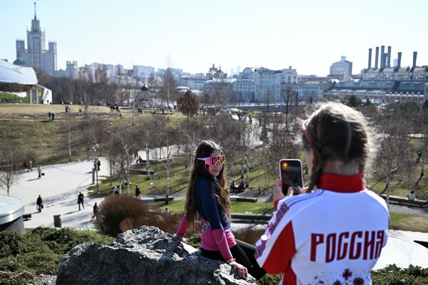 فتاتان تلتقطان الصور الذكارية وسط حديقة زاريادي التي تشهد حركة نشطة للزوار الذي يظهرون في خلفية الصورة. - سبوتنيك عربي