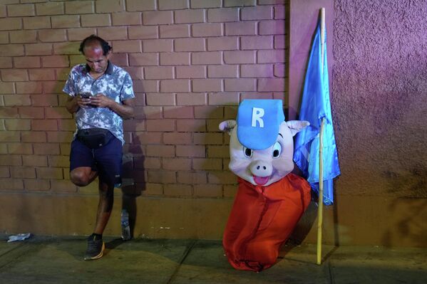 يستريح أحد مؤيدي المرشح الرئاسي رافائيل لوبيز ألياجا، من حزب التجديد الشعبي في البيرو، بجوار زي "بوركي"، وهو لقب لوبيز ألياغا، خارج قاعة المناظرة الرئاسية، قبل انتخابات 12 أبريل في ليما، بيرو، الثلاثاء 31 مارس 2026 - سبوتنيك عربي