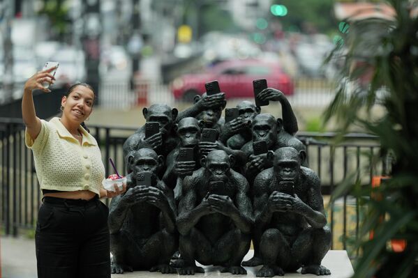 امرأة تلتقط صورة سيلفي بجوار منحوتة بعنوان "منفصل" للفنان البرازيلي بيتو غاتي على رصيف شارع باوليستا في ساو باولو. البرازيل. - سبوتنيك عربي