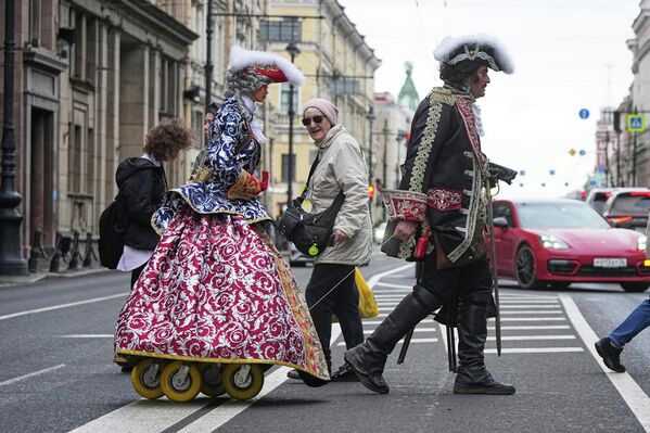 رجل يرتدي زي القيصر الروسي بطرس الأكبر، يسحب خلفه تمثالا للإمبراطورة، يلتقط الصور مع المارة في أحد شوارع مدينة سان بطرسبورغ، في طريقة لكسب المال.  - سبوتنيك عربي