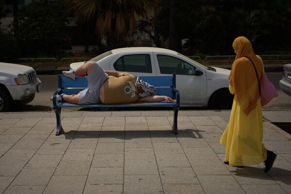 رجل ينام على مقعد موجود على كورنيش البحر في العاصمة اللبنانية بيروت.  - سبوتنيك عربي