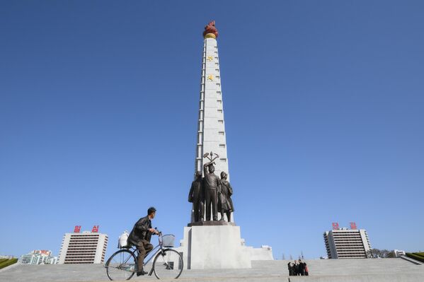 نصب تذكاري لفكرة جوتشي في بيونغ يانغ، ويظهر أمامه شاب يستقل دراجته الهوائية. - سبوتنيك عربي