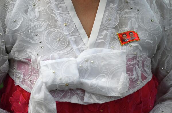 شارة عليها صور كيم جونغ إيل وكيم إيل سونغ على ملابس أحد سكان بيونغ يانغ. - سبوتنيك عربي