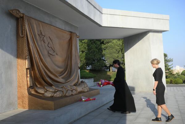 الأب أندريه كالتشيف، رئيس وفد أبرشية فلاديفوستوك، وزوجته خلال مراسم وضع الزهور عند نصب التحرير في بيونغ يانغ. - سبوتنيك عربي