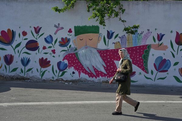 سيدة تمر أمام لوحة مرسومة على جدار في أحد شوارع العاصمة طهران. - سبوتنيك عربي