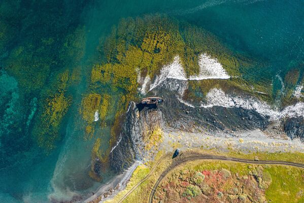صورة جوية لقارب صيد جرفته عاصفة إلى الشاطئ في رأس نيميتسكي بشبه جزيرة ريباتشي في روسيا. - سبوتنيك عربي