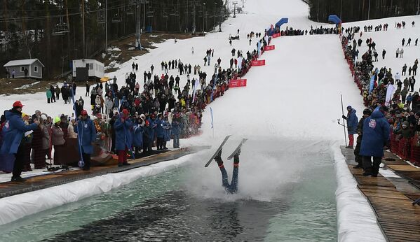 مشاركون بزي كرنفالي خلال مهرجان غورنولوزنيك السنوي في منتزه بوبروفي لوغ بكراسنويارسك يخوضون تحدي التزلج على الجليد والألواح لعبور مسبح بطول 25 متراً عند قاعدة منحدر التزلج. - سبوتنيك عربي