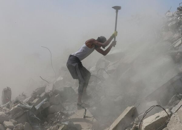 عامل فلسطيني يكسّر الخرسانة أثناء عمله على الأنقاض في خان يونس، جنوبي قطاع غزة - سبوتنيك عربي