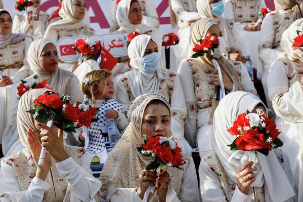 عرائس فلسطينيات يحملن الورود في حفل زفاف جماعي لـ50 عريسًا في مدينة غزة، نظمته مؤسسة الإغاثة الإنسانية (IHH) - سبوتنيك عربي