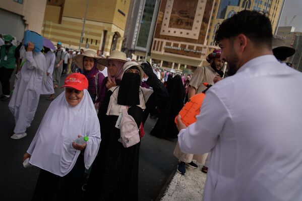 يتفاعل أحد الحجاج المسلمين مع متطوع يرش الماء لتبريدهم خارج المسجد الحرام خلال موسم الحج السنوي في مكة المكرمة، المملكة العربية السعودية، الأحد 24 مايو 2026. - سبوتنيك عربي