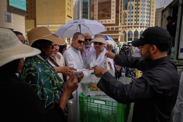 يوزع متطوع الماء والوجبات الخفيفة على المعتمرين المسلمين خارج المسجد الحرام خلال موسم الحج السنوي في مكة المكرمة، المملكة العربية السعودية، الأحد 24 مايو 2026. - سبوتنيك عربي