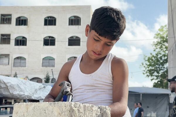 طفل فلسطيني يحمل المطرقة بدل القلم ويعمل في البناء لتأمين طعام عائلته مايو 2026  - سبوتنيك عربي