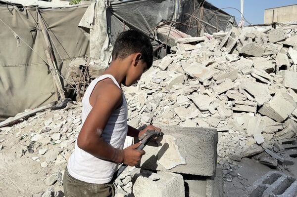 طفل فلسطيني يحمل المطرقة بدل القلم ويعمل في البناء لتأمين طعام عائلته مايو 2026  - سبوتنيك عربي