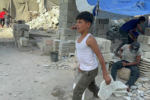 طفل فلسطيني يحمل المطرقة بدل القلم ويعمل في البناء لتأمين طعام عائلته مايو 2026  - سبوتنيك عربي