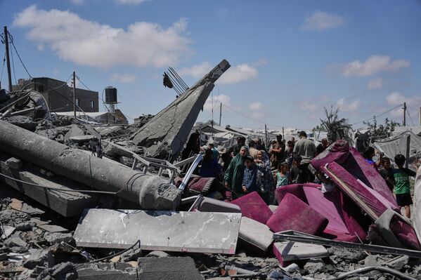 فلسطينيون يتفقدون أنقاض مبنى دُمّر جراء غارة جوية إسرائيلية في خان يونس، جنوبي قطاع غزة. - سبوتنيك عربي